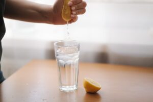 Female,Hand,Squeeze,Lemon,Juice,In,Glass,With,Water.,Water